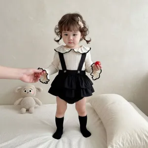 Detailansicht des Strick Puppenkragen Träger-Sets und süßen Babystramplers für Kleinkinder.