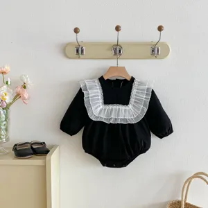 Detailed view of black baby romper featuring delicate white lace ruffle collar and long sleeves.