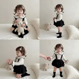 Nahaufnahme des Kleinkind Mädchen Strick Puppenkragen Top und Trägerhose Sets im gemütlichen Stil.