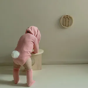 Grenouillère bébé à manches longues avec oreilles de lapin, queue duveteuse et chaussettes.