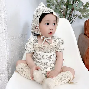 Floral baby romper detail shot featuring delicate lace bonnet and matching socks for summer wear.