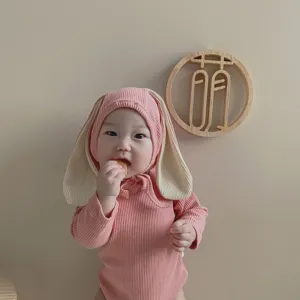 Gros plan bébé montrant barboteuse rose côtelée manches longues à capuche oreilles lapin.