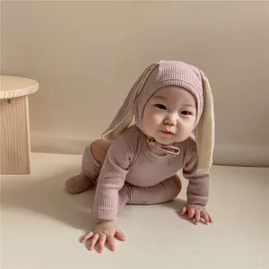 Vue détaillée d'un bébé rampant dans un ensemble barboteuse oreilles de lapin côtelé rose.