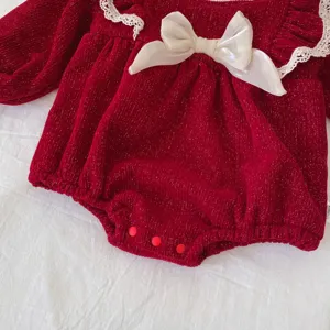 Close-up of red baby girl velvet romper featuring cute white lace collar and bow.