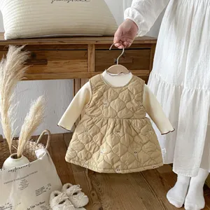 Dettaglio di abito gilet trapuntato per bambini e top bianco, vestito caldo invernale morbido.