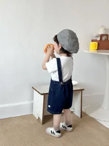 Vista dettagliata di salopette in denim coreane per bambini con t-shirt e berretto.