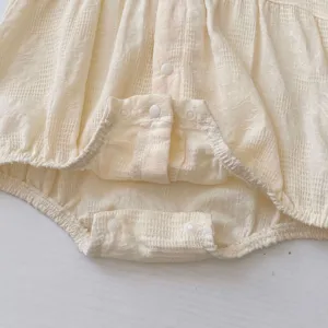 Dettaglio tutina neonato in puro cotone con delicata trama waffle e chiusura a bottoni automatici.