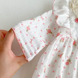 Détail de la manche de la robe en coton pour bébé avec joli imprimé floral rose.