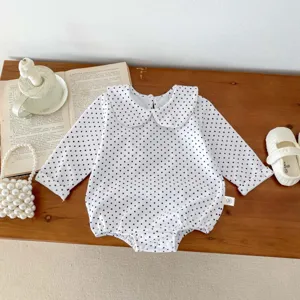 Vista dettagliata di un grazioso body per neonato a maniche lunghe con pois neri.