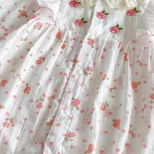 Détail de grenouillère bébé fille à fleurs, imprimé roses nœuds, coton dentelle douce.
