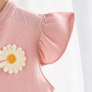 Primer plano del hombro del pelele de bebé rosa con bordado de margarita y volantes.