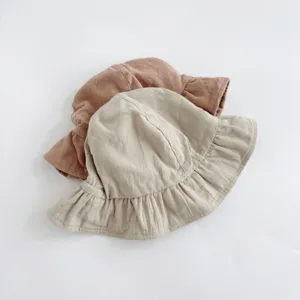 Detailed view of cute solid color baby sun hat with ruffled brim, soft linen fabric texture.