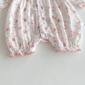 Détail de grenouillère en coton pour bébé fille, joli imprimé floral rose et volants fins.