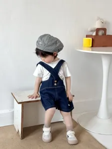 Set estivo per neonati: salopette in denim con t-shirt bianca e cappello a quadretti.
