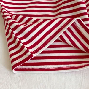 Dobladillo detallado de ropa de bebé a rayas rojas y blancas, tela de punto muy suave.