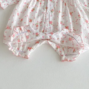 Détail en gros plan de la barboteuse pour bébé fille avec motif floral et volants.