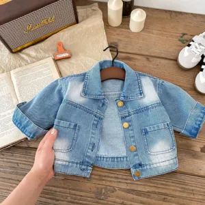 Dettaglio giacca di jeans per neonato con lavaggio chiaro, bottoni in metallo e tasche.