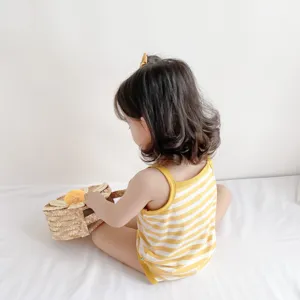 Infant strap romper detail view, showing soft cotton fabric, yellow and white stripes.