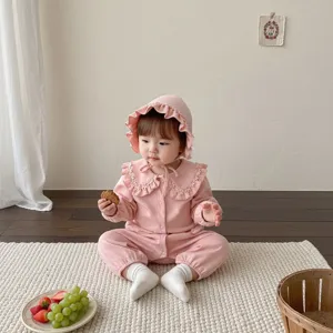 Détail de grenouillère rose pour bébé avec volants délicats et design à manches longues.