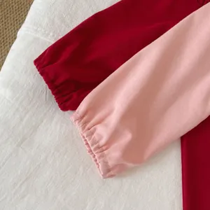 Vue détaillée des poignets de vêtements pour bébés, tissu côtelé doux, élastique, rose et rouge.