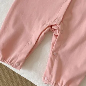 Gros plan détail de grenouillère bébé rose en tricot côtelé avec boutons pression pratiques.