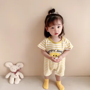 Adorable baby girl wearing yellow and white striped short sleeve romper with cute smiling face.