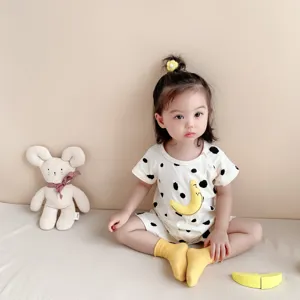Cute infant summer romper detail, soft cotton baby clothes with playful cow print and moon motif.