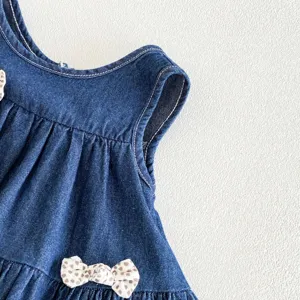 Dettaglio ravvicinato del grazioso vestito di jeans per bambina con fiocco, tessuto morbido.