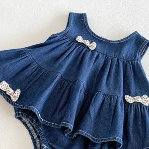 Primo piano dettagliato della graziosa tutina abito in denim per bambina con fiocchi a pois.