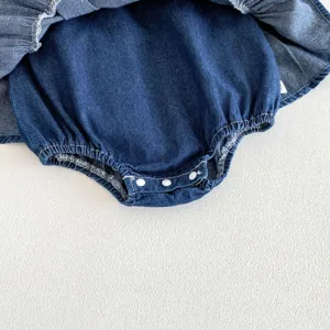 Dettaglio grazioso vestito tutina in denim per bambina, cotone lavato blu scuro con comodi bottoni.