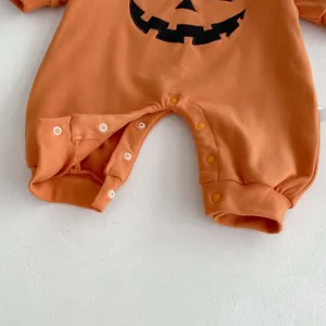 Close-up detail of orange baby romper with black pumpkin embroidery, soft cotton snaps.
