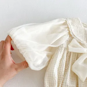 Detalle en primer plano de pelele de manga larga para bebé niña, cuello de encaje abombado.