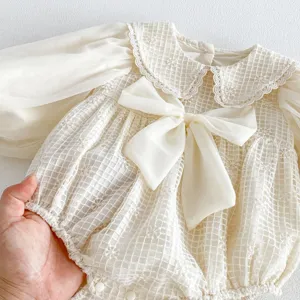 Primer plano detalle mameluco bebé niña manga larga, tela encaje blanco, lindo cuello lazo.