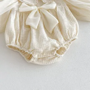 Detalle de mameluco de manga larga para niña bebé con encaje, lazo y cuello de muñeca.