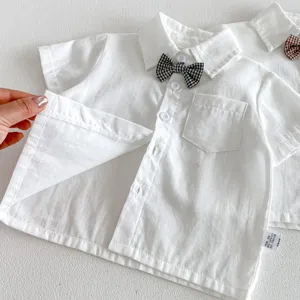 Detailed view of white toddler boy short sleeve shirt with checkered bow tie and pocket.