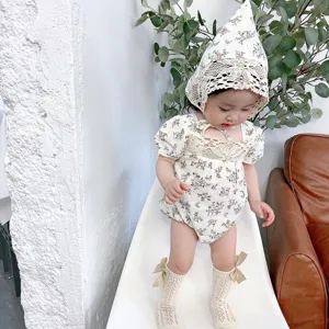 Cute baby floral romper detail shot featuring lace bonnet and bow socks for summer wear.