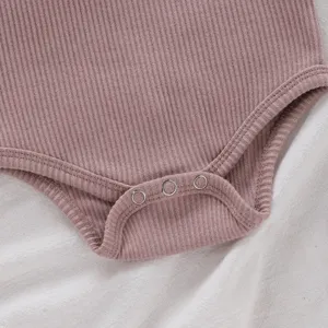 Vue rapprochée d'un body bébé côtelé doux avec boutons-pression pour changer facilement les couches.