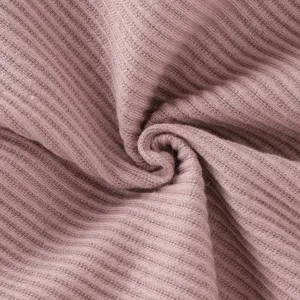 Gros plan sur un tissu en maille côtelée rose poussiéreux, texture douce et fine.