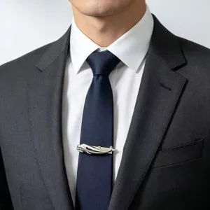 Détail en gros plan d'un pince-cravate dauphin argenté sur cravate bleue et chemise.