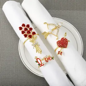 Primo piano di eleganti portatovaglioli dorati con rose rosse e cuore per decorazione tavola.