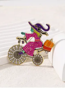 Halloween witch riding bicycle brooch detail, alloy rhinestone enamel pin jewelry accessory.