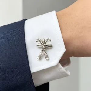 Gros plan détaillé de boutons de manchette club et balle de golf argentés sur chemise.