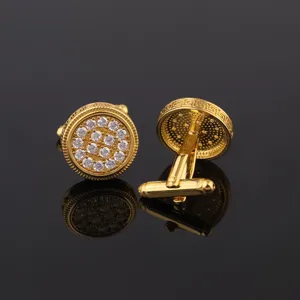 Détail de boutons de manchette ronds dorés avec zircone et bordure grecque classique pour hommes.