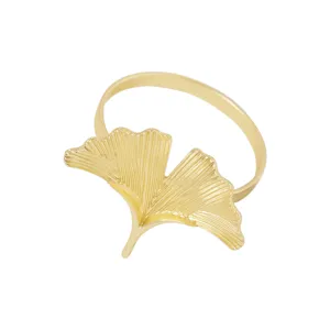 Detalle de servilletero de hoja de ginkgo de metal dorado, accesorio de mesa elegante.