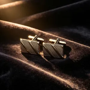 Gold metal square cufflinks detail view, elegant textured pattern for business formal wear.