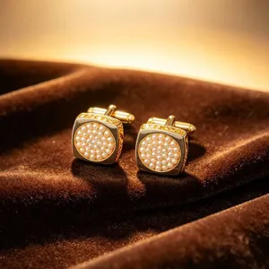 Gros plan détail de boutons de manchette carrés dorés perle zircon pour chemise homme.