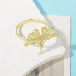 Detalle servilletero de metal hoja de ginkgo dorada, decoración de mesa elegante.