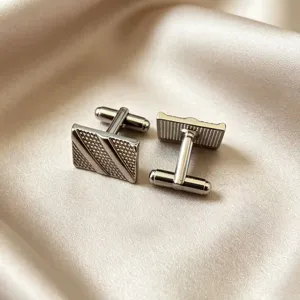 Close-up detail of silver business cufflinks, textured pattern, elegant men accessory style.