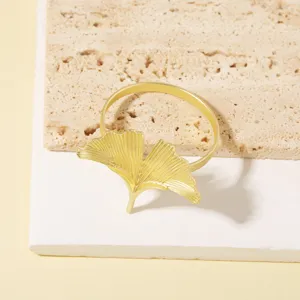 Detalle servilletero de metal hoja de ginkgo dorada, decoración de mesa elegante.