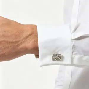 Close-up of elegant square brushed metal cufflinks worn on a white French cuff shirt detail.